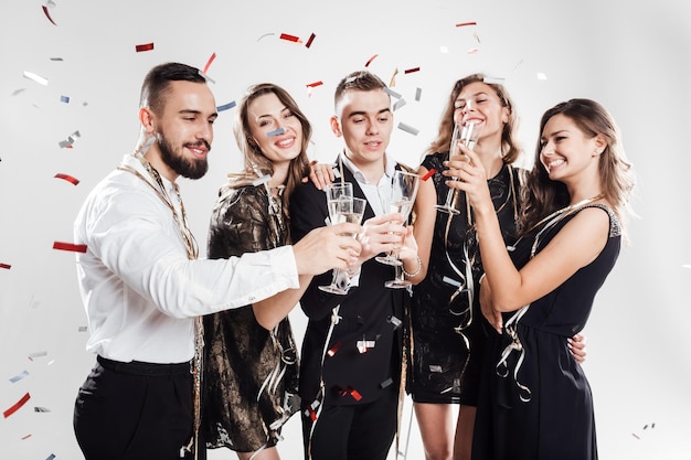 Amigos con ropa elegante y elegante sonríen juntos sosteniendo copas de champán en las manos