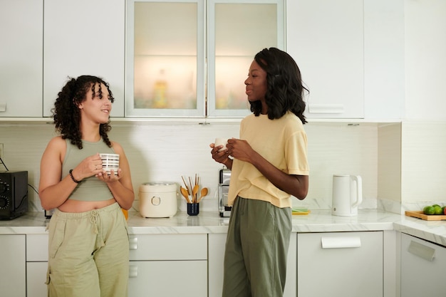 Amigos en ropa de estar tomando café en la cocina y discutiendo noticias