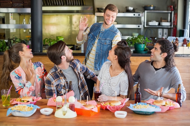 Amigos saludando a joven en restaurante