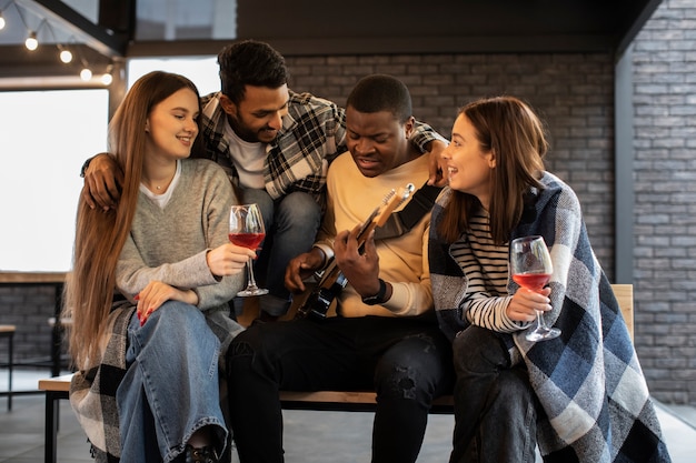 Amigos se divertindo enquanto ouvem o amigo tocando violão