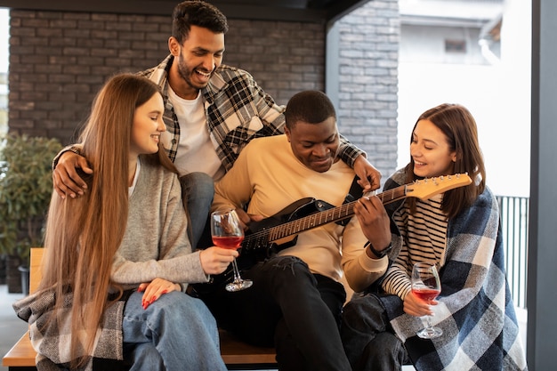 Amigos se divertindo enquanto ouvem o amigo tocando violão