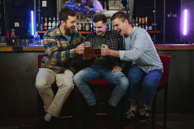 Amigos se divertindo Jovens felizes em roupas casuais bebendo cerveja no pub