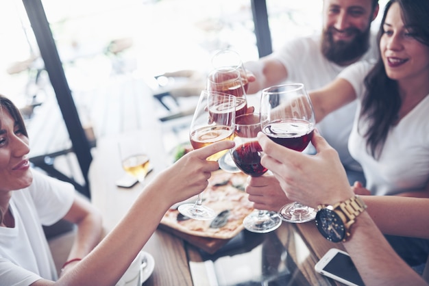 Amigos se reuniram à mesa com comida deliciosa com taças de vinho tinto para comemorar uma ocasião especial