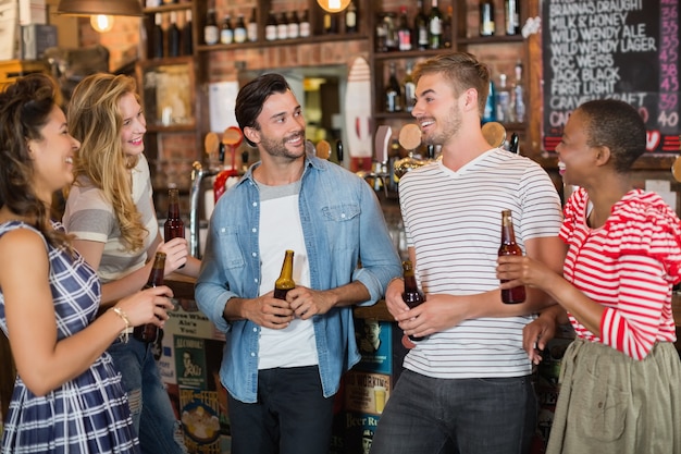 Amigos segurando garrafas de cerveja em bar