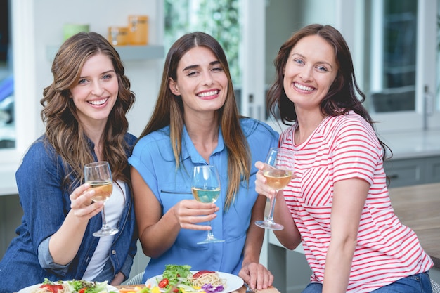 Amigos, segurando o copo de vinho enquanto come refeição