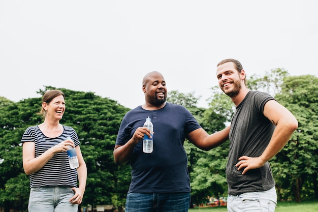 Amigos, segurando uma garrafa de água e conversando no parque