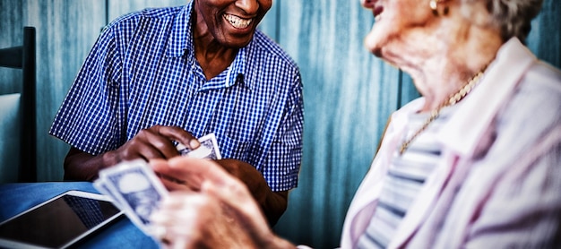 Amigos sênior do sexo masculino e feminino sorrindo, jogando cartas