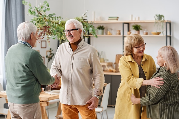 Amigos senior saludándose durante su reunión en casa