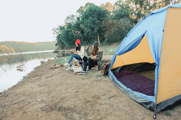 Amigos sentados ao lado do lago na floresta