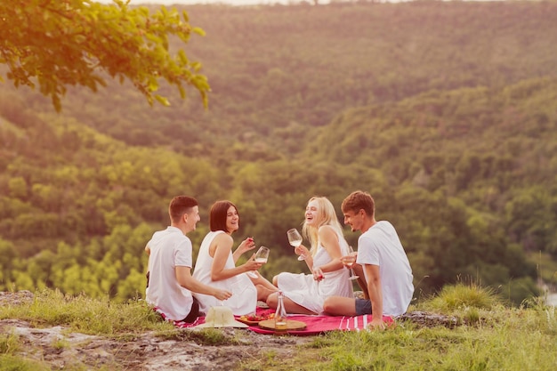 amigos sentados en la montaña y tintineando copas de vino