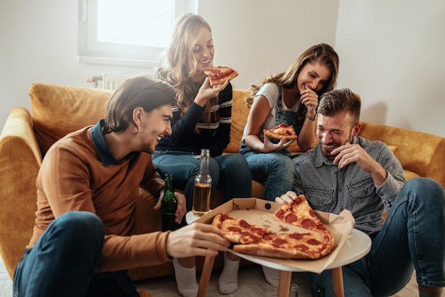 Amigos sentados en la sala de estar y comiendo pizza.