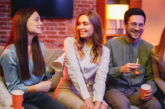 Amigos sentados en un sofá en una habitación acogedora y celebrando un cumpleaños