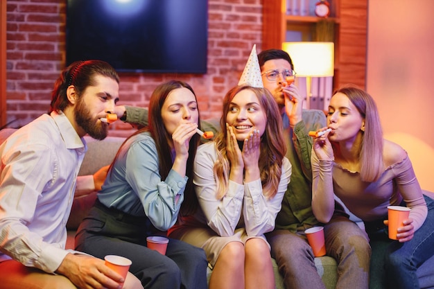 Amigos sentados en un sofá en una habitación acogedora y celebrando un cumpleaños