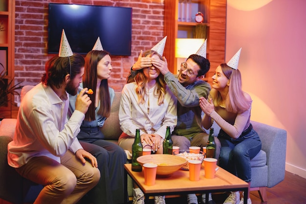 Amigos sentados en un sofá en una habitación acogedora y celebrando un cumpleaños