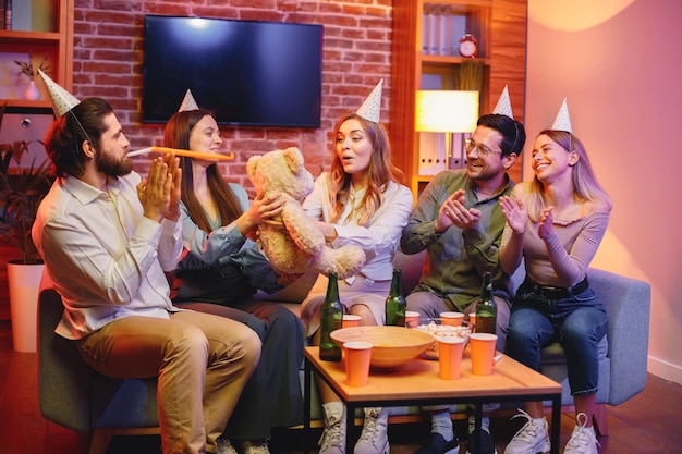 Amigos sentados en un sofá en una habitación acogedora y celebrando un cumpleaños