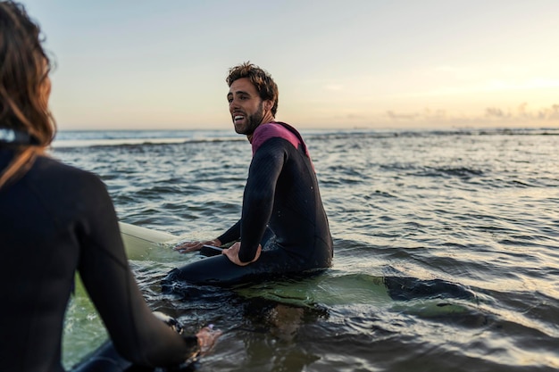 Amigos sentados en tablas de surf en el océano y divirtiéndose