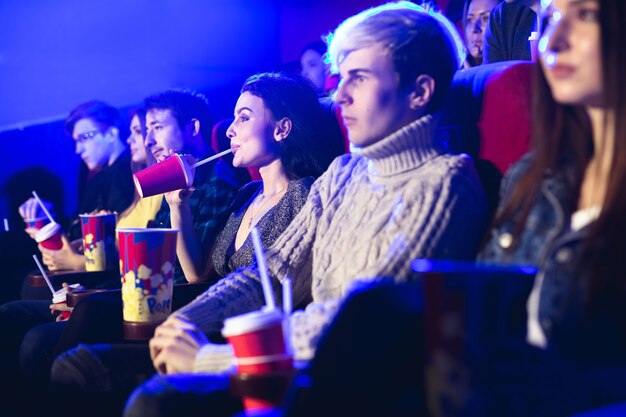 Amigos sentam-se e comem pipoca juntos enquanto assistem a filmes no cinema