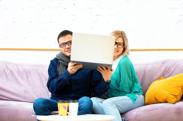 Los amigos se sientan en el sofá charlando y usando una computadora de escritorio