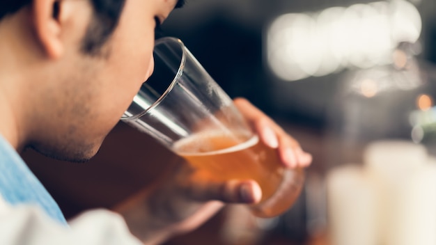 Los amigos sonríen, disfrutan de la fiesta en el bar y hablan y tintinean botellas con bebidas.