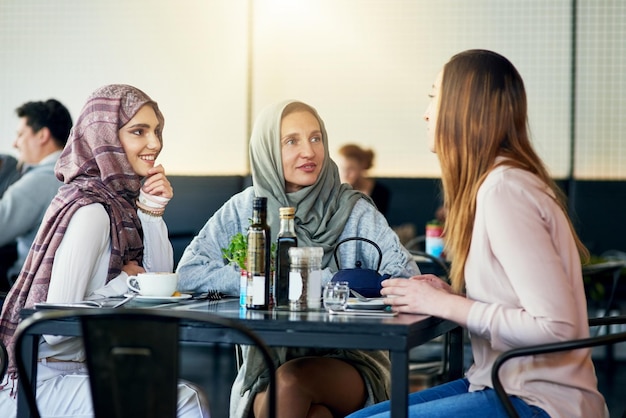 Los amigos sonríen y las mujeres musulmanas en la cafetería se unen y hablan juntas Cafetería feliz y grupo de chicas islámicas o personas chatean conversación y discusión para reuniones sociales en el restaurante