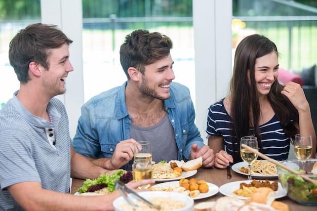 Amigos sonriendo mientras cena en la mesa