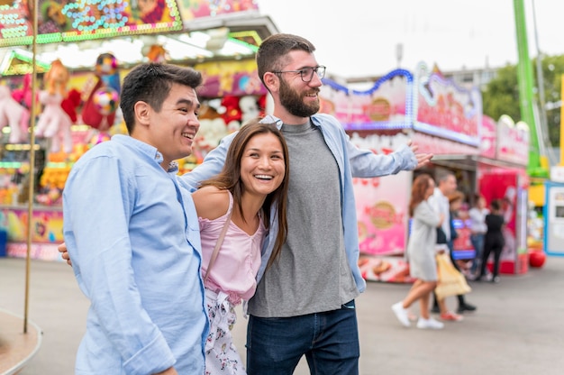 Amigos sonrientes abrazados en el parque de atracciones