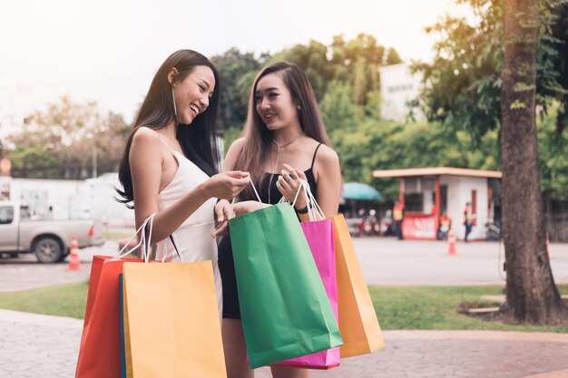 Amigos sonrientes con bolsas de compras de pie en la acera