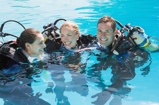 Amigos sonrientes en el entrenamiento de buceo en la piscina