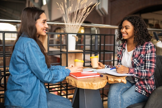 Foto amigos sonrientes haciendo los deberes juntos en un café