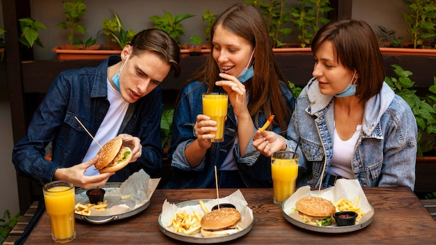 Amigos sonrientes con hamburguesas con papas fritas