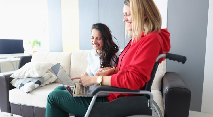 Foto amigos sonrientes mirando fotos en una laptop mujer en silla de ruedas y personas discapacitadas