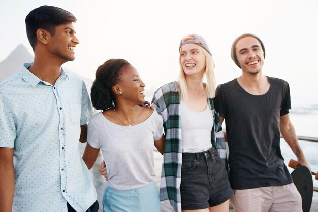 Amigos sonrientes de pie contra el mar