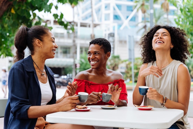 Amigos sonrientes usando el teléfono móvil mientras están sentados en un café