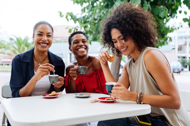 Amigos sonrientes usando teléfonos inteligentes mientras están sentados en un restaurante