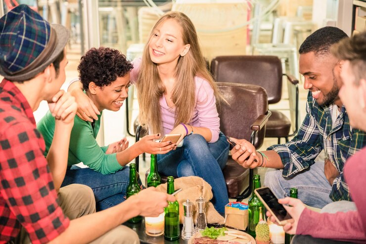Foto amigos sonrientes usando teléfonos mientras están sentados en un restaurante