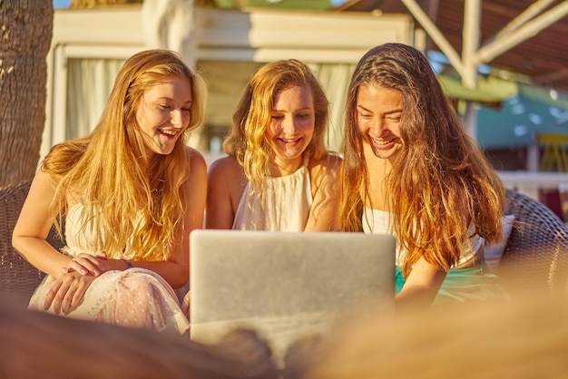 Amigos sorridente usando laptop na cidade durante um dia ensolarado