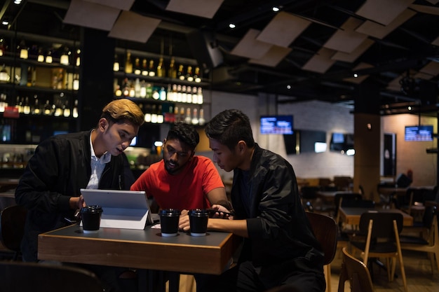 Foto amigos sorridente usando tablet digital enquanto sentado na mesa no café