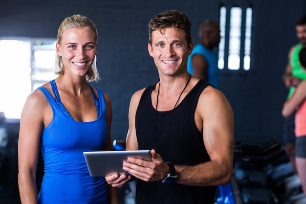 Amigos sorridentes com tablet digital no ginásio