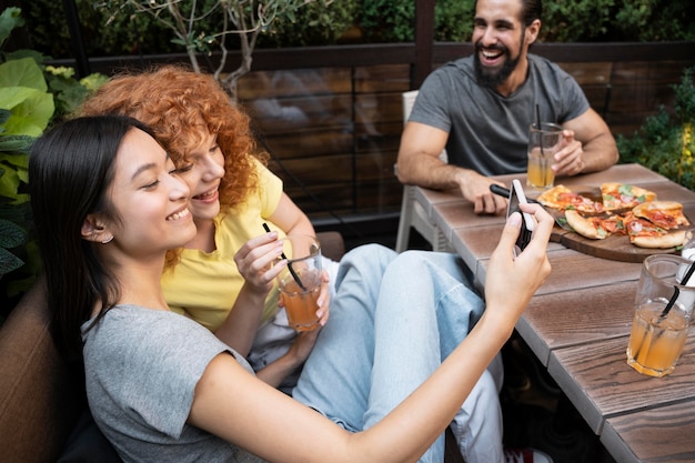 Amigos sorridentes de tiro médio com pizza