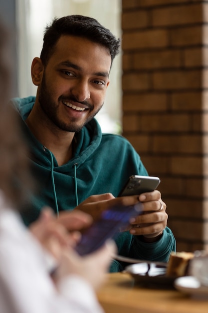 Amigos sorridentes de vista lateral com smartphone