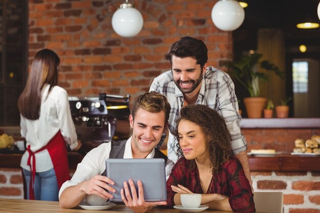 Amigos sorridentes que olham o tablet digital