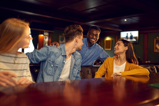Foto amigos sorridentes se divertem no balcão do bar. grupo de pessoas relaxando no bar, estilo de vida noturno, amizade, celebração de evento
