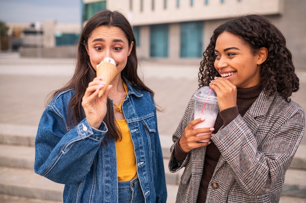 Foto amigos sorridentes tomando sorvete e milkshakes ao ar livre