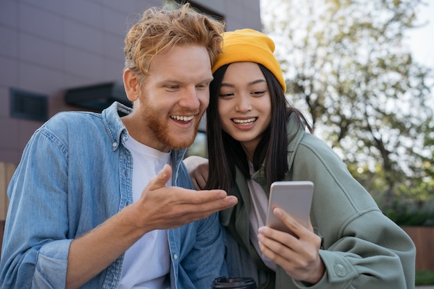 Amigos sorridentes usando o telefone celular assistindo a compras de vídeo online