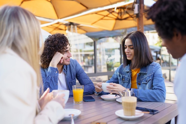 Amigos sorridos a tomar o pequeno-almoço num café.