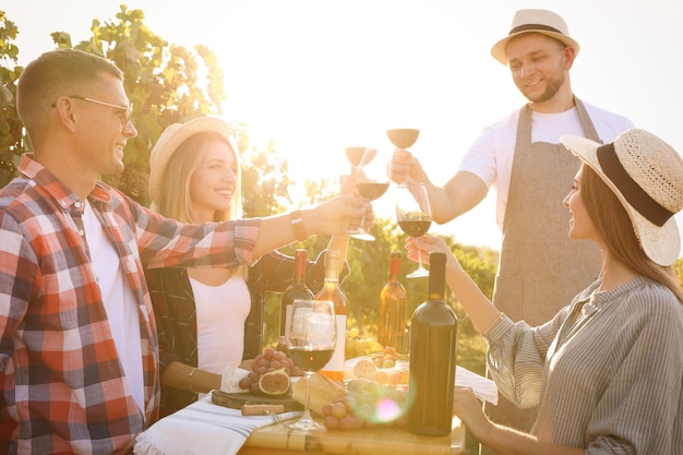 Amigos sosteniendo copas de vino y divirtiéndose en el viñedo