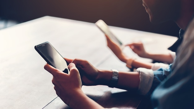 Amigos con teléfono inteligente en la cafetería, durante el tiempo libre. El concepto de uso del teléfono es e