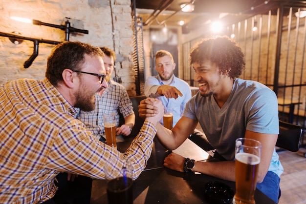 Amigos, tendo queda de braço no pub.