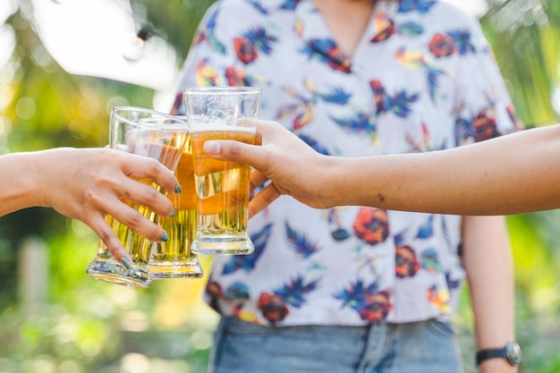 Amigos tilintando uma garrafa de cerveja durante o acampamento ao ar livre