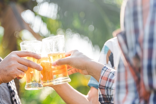 Amigos tilintando uma garrafa de cerveja durante o acampamento ao ar livre